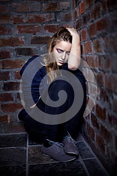 Feeling like theres no escape. Abused young woman huddled and crouching in a corner.