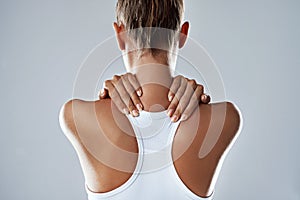 Feeling a little strain in her neck. Studio shot of an athletic young woman holding her neck in pain against a grey