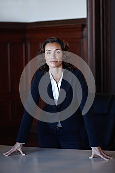 Feeling powerful. Attractive legal woman leaning on a desk and smiling at the camera.