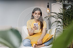 Feeling safe. Attractive multi-ethnic women 25s relaxed at home on couch scrolling phone