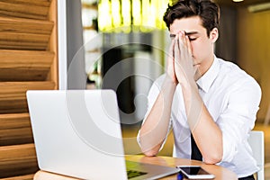 Feeling sick and tired, Frustrated young man massaging his nose and keeping eyes closed while sitting at his working place in offi