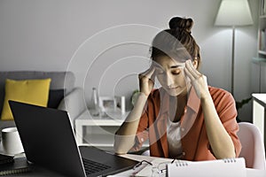 Feeling tired and stressed. Young Asian woman sitting with eyes closed from exhaustion and tiredness during working at home office