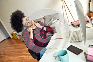 Feeling tired after studying online all day. Young afro american woman massaging neck and relaxing after long computer