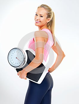 Feeling trim and fit. a young woman holding a scale and eating an apple.
