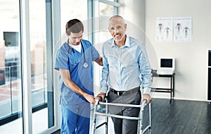 Feels great to be hitting the road to recovery. Portrait of a senior patient with a walker getting assistance from a