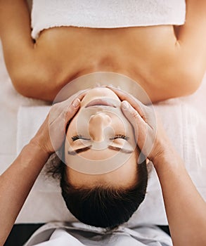 This feels like heaven. a beautiful young woman getting a head massage at a spa.