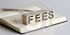 The FEES sign on a wooden block on notebook background