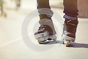 Feet of aggressive inline rollerblader on outdoor skatepark