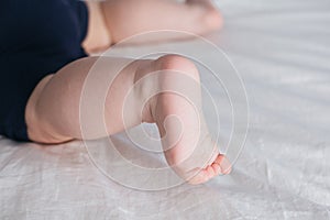 Feet of baby boy on bed. Legs on a white background