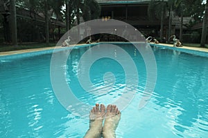 Feet on the background of the blue water of the swimming pool