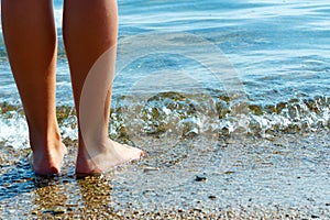 Feet barefoot girl near the water`s edge by the sea