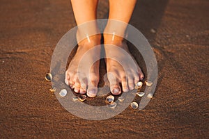 Feet on a beach with cockleshells