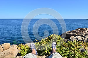 Feet in blue sneakers hanging of the cliff