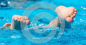 Feet in the blue water of the pool