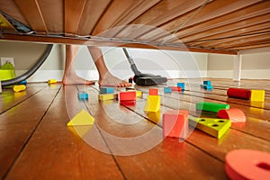 Feet of boy clean floor with mess under the bed