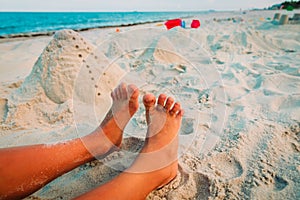 Feet of boy play with sand on beach and toys on beach