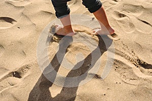 Feet of boy walking on the sand of the beach