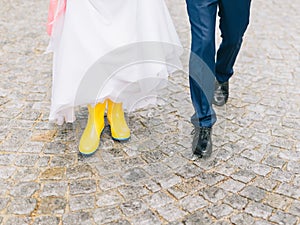 Feet of the bride and groom walk in rainy weather