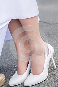 Feet of the bride`s girl in white wedding shoes