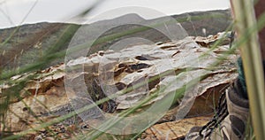 Feet of caucasian male survivalist walking on rocky mountain, using walking poles