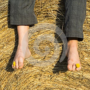 Feet of child boy sitting on haystack