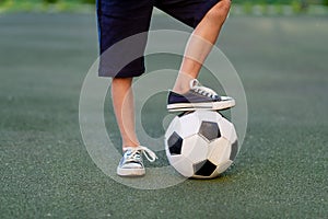 Feet of a child boy with a soccer ball on a green lawn on a football field, sports section, training