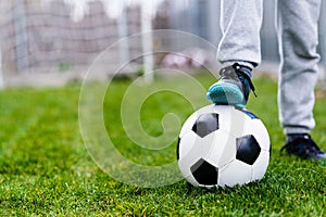 Feet of child on football / soccer ball on grass