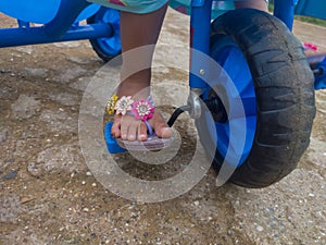 the feet of a child wearing sandals pedaling