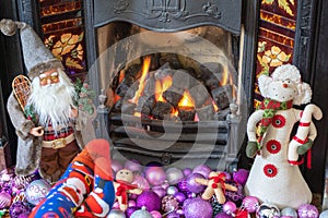 Feet in Christmas socks by the fireplace. Woman relaxes by warm fire and warming up her feet in funny socks. Close up on feet.