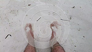 Feet close-up on the sand of the sea beach. Sea water washes the feet. Rest at the sea. Summer sunny day