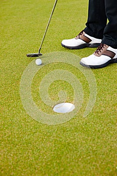 Feet, club and ball for hole on golf course, contest and practice for competition or tournament. Closeup, shoes and