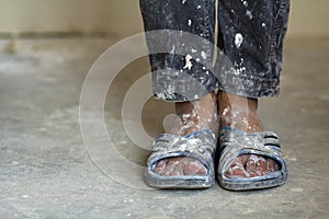 Feet of a construction worker in old dirty clothes and shoes