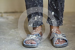 Feet of a construction worker in old dirty clothes and shoes