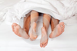 Feet of couple in bed