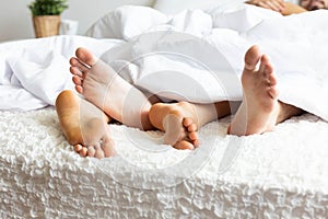Feet of couple on bed and cross