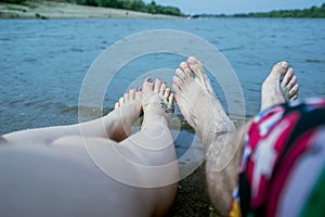 Feet of the couple, by the river, enjoy a beach holiday, buzz and relaxation