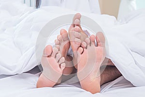 Feet of couple side by side in bed