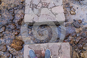 Feet crossing river on rocks