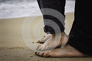 Feet of daddy and boy watching the sea from the beach