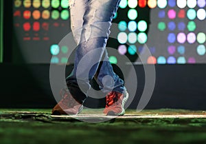 Feet of a dancer on stage doing hip hop dancing stance with background neon lights