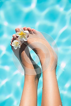 Feet dangling over swimming pool with flowers