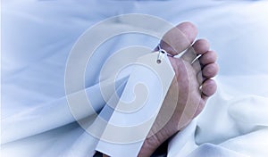 Feet of a dead body, identification tag, close-up in white sheets