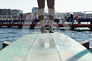 feet of a diver ready to dive off a blue diving board pocking out over the waves in a bay and protected sea bath in Geelong,