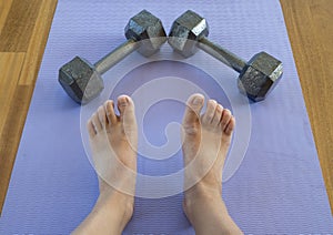 Feet and Dumbbells after a home workout on a yoga mat