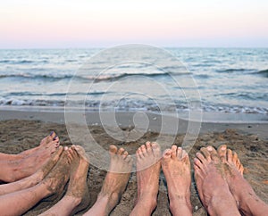 Feet of a family barefoot by the sea on the beach in summer
