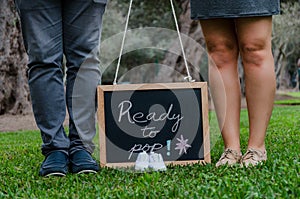 Feet of father and mother with baby shoes and a black slate