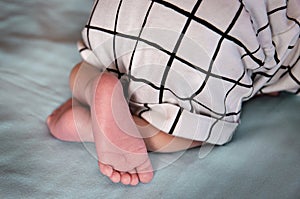 Feet and fingers of a newborn baby, with grey background out of focus.