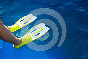 Feet with flippers on the blue sea while snorkeling.