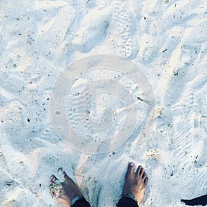 feet and footprints on the white sand beach