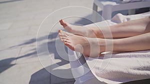 Feet of a girl with a pedicure on vacation. Bare feet over blue swimming pool water